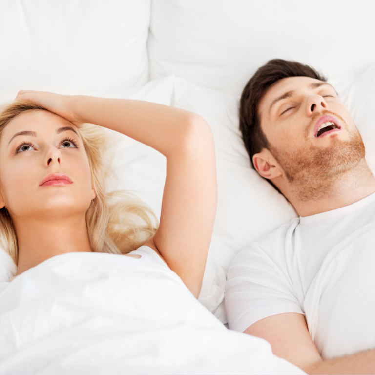 woman laying next to man in bed annoyed by his loud snoring